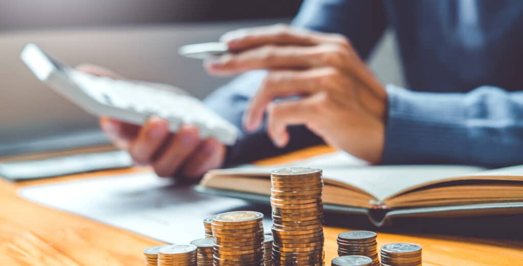 Man calculating finances with a calculator, coins in the background – a symbol of banking security.