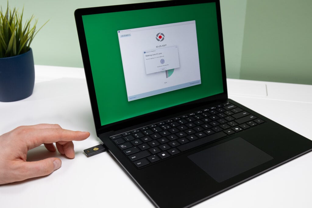 Image showing a FIDO security key plugged in to a laptop and an employee preparing to touch it to authenticate to their local Windows system using Rublon MFA as an example of multi-factor authentication.